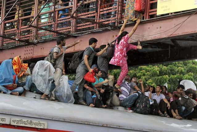 A Bangladeshi woman tries to jump onto an overcrowded train from a bridge to travel home for Eid al-Fitr in Dhaka, Bangladesh, Wednesday, August 7, 2013. Muslims across the world are preparing for the arrival of Eid al-Fitr, the festival marking the end of the Muslim fasting month of Ramadan. (Photo by A. M. Ahad/AP Photo)