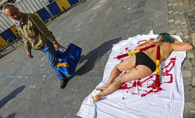 An animal rights protester, covered in fake blood, lies on pavement in central Brussels calling for the abolition of bullfighting, on August 8, 2013. (Photo by Yves Herman/Reuters)