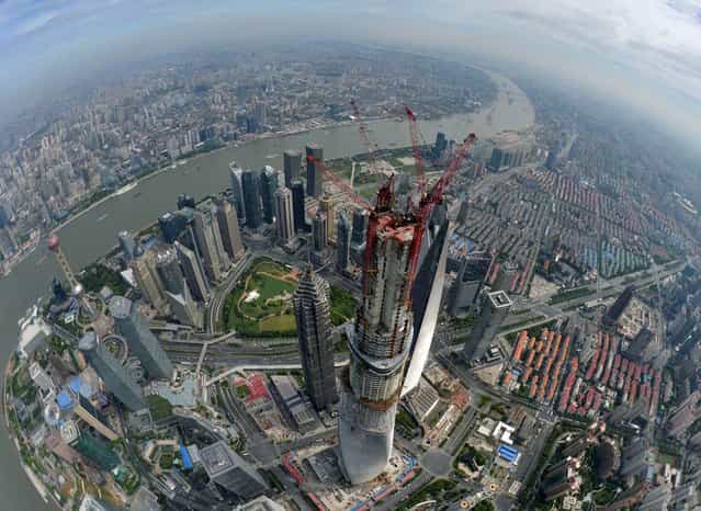 This photo taken Saturday, August 3, 2013, shows an aerial view of Shanghai Tower after a final beam is installed in Shanghai, China. A topping-out ceremony was held Saturday for China's tallest building in the financial hub of Shanghai when the final beam was hoisted to the top of the skyscraper and installed in a flag-waving ritual. At 632 meters (2,073 feet), the Shanghai Tower in the city's Pudong district is the world's second-tallest building, surpassed only by Dubai's Burj Khalifa, which soars 829.8 meters (2,722 feet). (Photo by AP Photo)