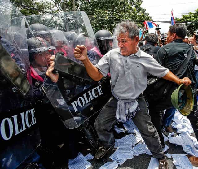 An anti-government protester fights police outside the parliament in Bangkok, on August 7, 2013. Thailand's parliament will debate a political amnesty bill that the protesters fear will allow the ex-premier Thaksin Shinawatra to return from exile without having to serve a jail sentence. (Photo by Athit Perawongmetha/Associated Press)