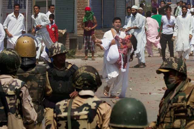 A Kashmiri man shouts for help as he carries an injured young woman after she was hit by a tear gas shell fired by Indian police during a clash with anti-India protesters, at Eidgah, or an open-air mosque, in Srinagar, India, Friday, August 9, 2013. Indian forces used tear gas and pellet guns to quell thousands of stone-throwing protesters who took to the streets after special Eid prayers on Friday in the Indian portion of Kashmir. (Photo by Dar Yasin/AP Photo)