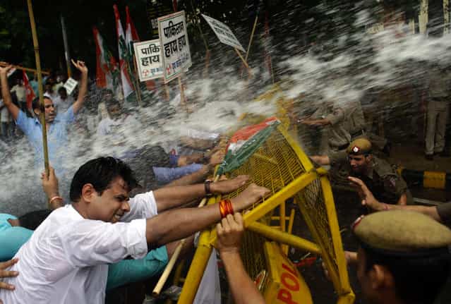 Activists of India's Congress party's youth wing try to break barricades as police use water cannon to stop them during a protest against the death of five Indian army soldiers in cross-border exchanges, New Delhi, India, Wednesday, Aug 7, 2013. India's army says five of its soldiers were killed and another wounded when Pakistani troops fired at a patrol near the cease-fire line in the disputed Himalayan region of Kashmir on Tuesday. The incident could threaten recent overtures aimed at resuming peace talks between the nuclear-armed rivals. (Photo by Tsering Topgyal/AP Photo)