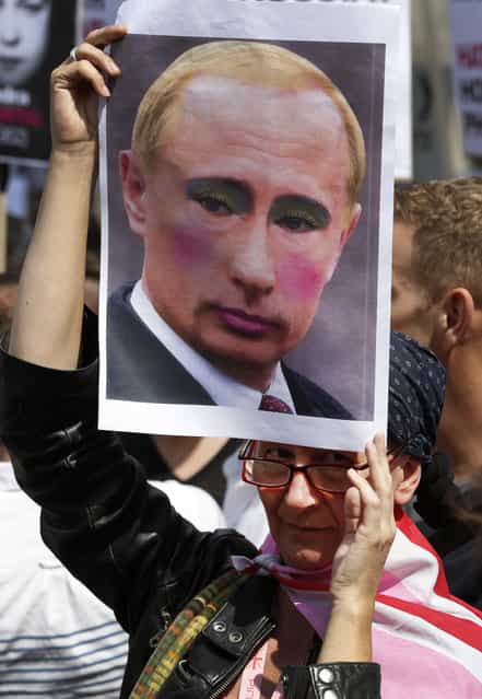 An activist holding a placard depicting Russian President Vladimir Putin participates at a protest against Russia's new law on gays, in central London, Saturday, August 10, 2013. Hundreds of protesters, called for the Winter 2014 Olympic Games to be taken away from Sochi, Russia, because of a new Russian law that bans [propaganda of nontraditional sexual relations] and imposes fines on those holding gay pride rallies. (Photo by Lefteris Pitarakis/AP Photo)