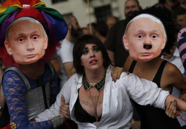Activists stage a theatrical play where gay people are restrained by others wearing masks depicting Russian President Vladimir Putin, during a protest against Russia's new law on gays, in central London, Saturday, August 10, 2013. Hundreds of protesters, called for the Winter 2014 Olympic Games to be taken away from Sochi, Russia, because of a new Russian law that bans [propaganda of nontraditional sexual relations] and imposes fines on those holding gay pride rallies. (Photo by Lefteris Pitarakis/AP Photo)