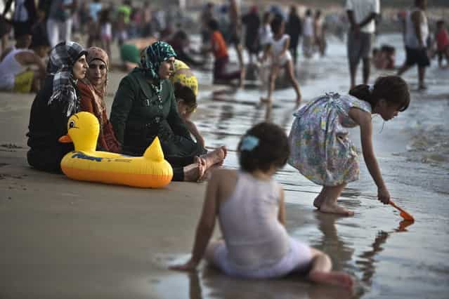 Palestinian women from Ramallah sit together at the shore of the Mediterranean sea at a beach in Tel Aviv during Eid al-Fitr, which marks the end of the holy month of Ramadan August 11, 2013. The Israeli Coordinator for Government Activities in the Territories' (COGAT) responsible for implementing Israel's civilian policy in the occupied West Bank and Gaza Strip, eased permit restrictions for thousands of Palestinians wanting to enter Israel following a security assessment, allowing many to enjoy the beaches along Israel's Mediterranean shoreline during the Eid al-Fitr holiday. (Photo by Nir Elias/Reuters)