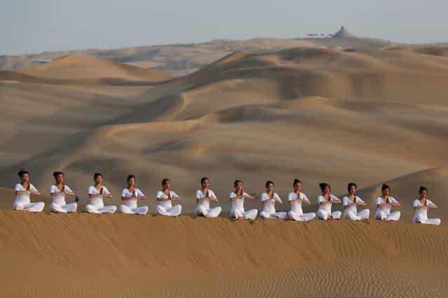 Dancers perform yoga on the dunes of Xiangshawan Desert, also called Sounding Sand Desert on July 20, 2013 in Ordos of Inner Mongolia Autonomous Region, China. (Photo by Feng Li/Getty Images)