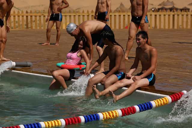 Toursits play in a swimming pool in Xiangshawan Desert, also called Sounding Sand Desert on July 20, 2013 in Ordos of Inner Mongolia Autonomous Region, China. Xiangshawan is China's famous tourist resort in the desert. It is located along the middle section of Kubuqi Desert on the south tip of Dalate League under Ordos City. Sliding down from the 110-metre-high, 45-degree sand hill, running a course of 200 metres, the sands produce the sound of automobile engines, a natural phenomenon that nobody can explain. (Photo by Feng Li/Getty Images)