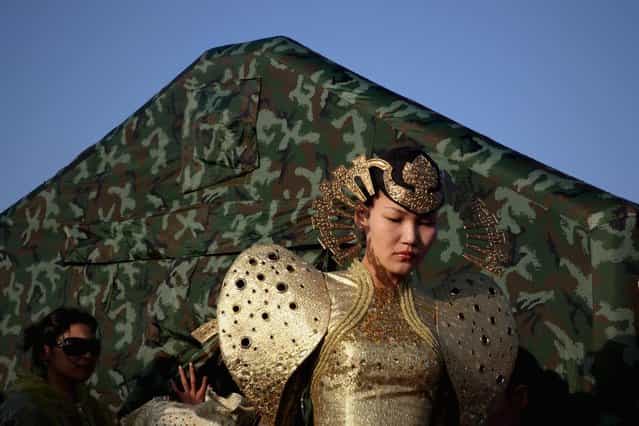 A model in Mongolia costumes prepares backstage after a Mongolian ritual ceremony in Xiangshawan Desert, also called Sounding Sand Desert on July 19, 2013 in Ordos of Inner Mongolia Autonomous Region, China. Xiangshawan is China's famous tourist resort in the desert. It is located along the middle section of Kubuqi Desert on the south tip of Dalate League under Ordos City. Sliding down from the 110-metre-high, 45-degree sand hill, running a course of 200 metres, the sands produce the sound of automobile engines, a natural phenomenon that nobody can explain. (Photo by Feng Li/Getty Images)