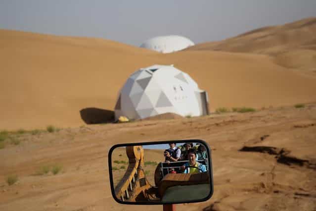 Toursits take bus past a toilet on a tour of Xiangshawan Desert, also called Sounding Sand Desert on July 19, 2013 in Ordos of Inner Mongolia Autonomous Region, China. Xiangshawan is China's famous tourist resort in the desert. It is located along the middle section of Kubuqi Desert on the south tip of Dalate League under Ordos City. Sliding down from the 110-metre-high, 45-degree sand hill, running a course of 200 metres, the sands produce the sound of automobile engines, a natural phenomenon that nobody can explain. (Photo by Feng Li/Getty Images)