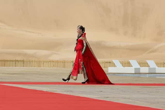 A model performs in Mongolia costumes in Xiangshawan Desert, also called Sounding Sand Desert on July 18, 2013 in Ordos of Inner Mongolia Autonomous Region, China. Xiangshawan is China's famous tourist resort in the desert. It is located along the middle section of Kubuqi Desert on the south tip of Dalate League under Ordos City. Sliding down from the 110-metre-high, 45-degree sand hill, running a course of 200 metres, the sands produce the sound of automobile engines, a natural phenomenon that nobody can explain. (Photo by Feng Li/Getty Images)