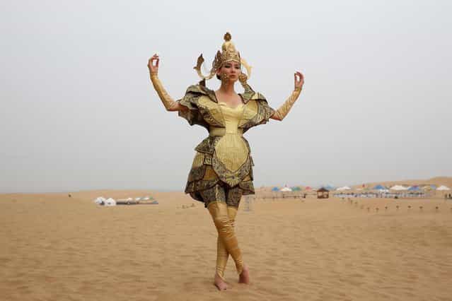 A model in Mongolia costumes poses for photos in Xiangshawan Desert, also called Sounding Sand Desert on July 21, 2013 in Ordos of Inner Mongolia Autonomous Region, China. Xiangshawan is China's famous tourist resort in the desert. It is located along the middle section of Kubuqi Desert on the south tip of Dalate League under Ordos City. Sliding down from the 110-metre-high, 45-degree sand hill, running a course of 200 metres, the sands produce the sound of automobile engines, a natural phenomenon that nobody can explain. (Photo by Feng Li/Getty Images)