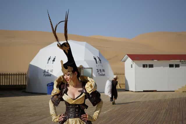 A model in Mongolia costumes prepares backstage in Xiangshawan Desert, also called Sounding Sand Desert on July 18, 2013 in Ordos of Inner Mongolia Autonomous Region, China. Xiangshawan is China's famous tourist resort in the desert. It is located along the middle section of Kubuqi Desert on the south tip of Dalate League under Ordos City. Sliding down from the 110-metre-high, 45-degree sand hill, running a course of 200 metres, the sands produce the sound of automobile engines, a natural phenomenon that nobody can explain. (Photo by Feng Li/Getty Images)