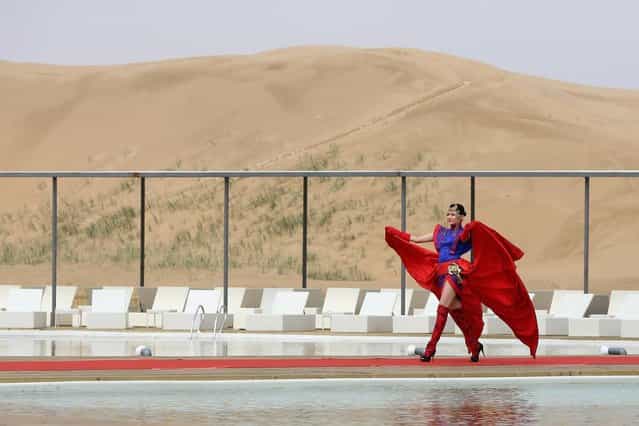 A model performs in Mongolia costumes near a swimming pool in Xiangshawan Desert, also called Sounding Sand Desert on July 18, 2013 in Ordos of Inner Mongolia Autonomous Region, China. Xiangshawan is China's famous tourist resort in the desert. It is located along the middle section of Kubuqi Desert on the south tip of Dalate League under Ordos City. Sliding down from the 110-metre-high, 45-degree sand hill, running a course of 200 metres, the sands produce the sound of automobile engines, a natural phenomenon that nobody can explain. (Photo by Feng Li/Getty Images)