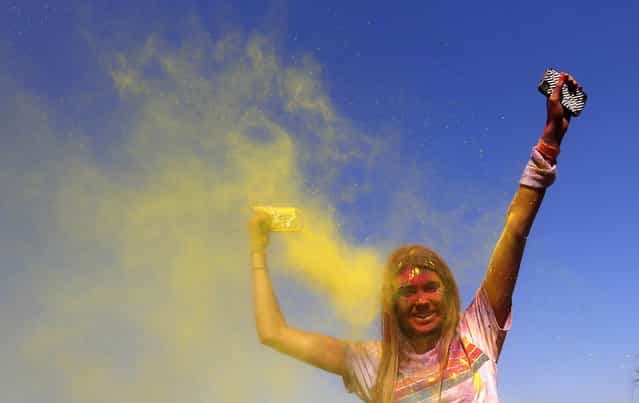 A woman throws yellow powder in the air after finishing the Colour Run at Centennial Park in Sydney August 25, 2013. According to organizers, 15,000 runners registered to complete the 5km (3 miles) course in Centennial Park on Sunday, being covered in blue, pink, orange and yellow powder on their way to the finish line. (Photo by Daniel Munoz/Reuters)