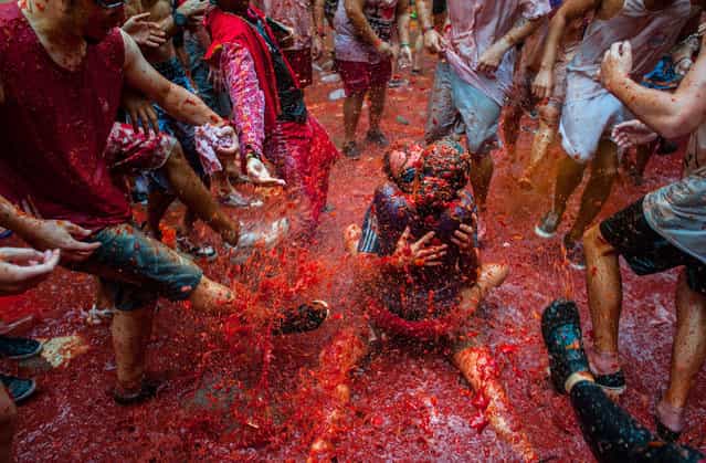 Two Revellers kiss each other covered in tomato pulp while participating the annual Tomatina festival on August 28, 2013 in Bunol, Spain. An estimated 20,000 people threw 130 tons of ripe tomatoes in the world's biggest tomato fight held annually in this Spanish Mediterranean town. (Photo by David Ramos/Getty Images)