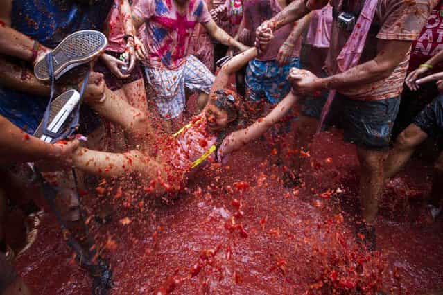 Revellers take part in the annual [Tomatina] festivities in Bunol, near Valencia, on August 28, 2013. Twenty thousands revellers hurled 130 tonnes of squashed tomatoes at each other, drenching the streets in red in a gigantic Spanish food fight known as the Tomatina. (Photo by Gabriel Gallo/AFP Photo)