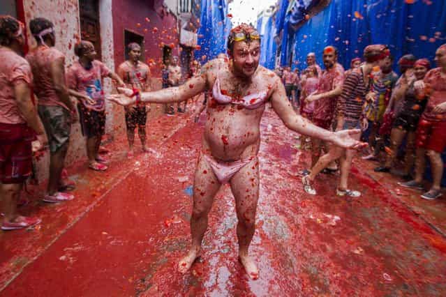 A man dressed in women's underwear enjoys a [tomato shower] during the traditional tomato fight [Tomatina] festival in Bunol, Spain, 28 August 2013. Bunol's city hall has sold 15,000 tickets to foreigners and with 5,000 residents, who don't have to pay, a total of 20,000 people have over 130,000 kg tomatoes to throw. Local authorities decided to sell tickets this year to avoid the traditional overcrowding of previous years in which over 50,000 people took part in the event. (Photo by Biel Alino/EPA)