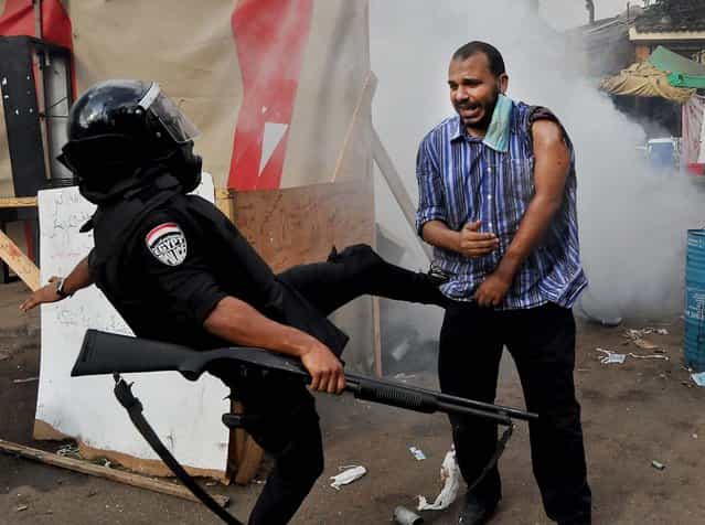 A policeman kicks a supporter of ousted Islamist President Mohammed Morsi as they clear a sit-in camp set up near Cairo University in Cairo's Giza district, on August 14, 2013. (Photo by Hussein Tallal/Associated Press)