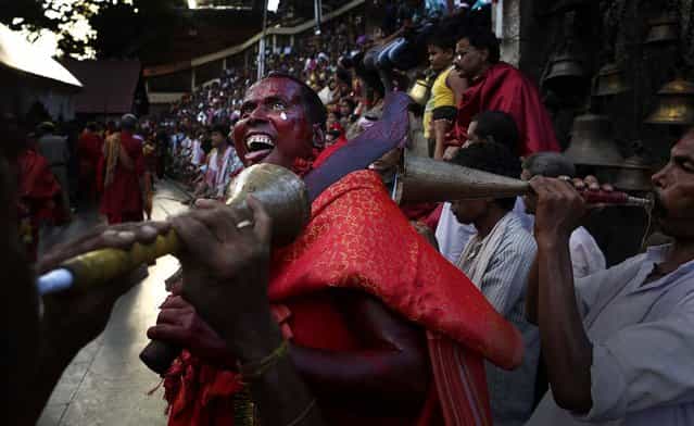 A Hindu priest, face smeared with color and sacrificial blood, gestures as he performs rituals during the two day long Deodhani festival at Kamakhya temple in Gauhati, India, on August 18, 2013. During this festival held to worship the serpent goddess, goats and pigeons are offered as sacrifice. (Photo by Anupam Nath/Associated Press)
