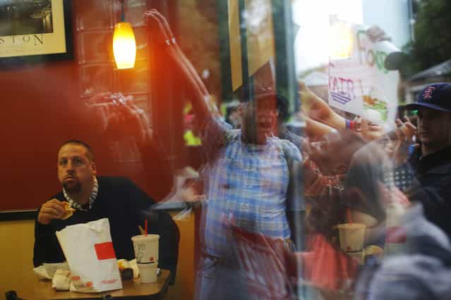 A man eats in a Burger King restaurant while demonstrators gather outside in Boston, Massachusetts August 29, 2013, part of a nation-wide fast food workers strike asking for $15 per hour wages and the right to form unions. (Photo by Brian Snyder/Reuters)