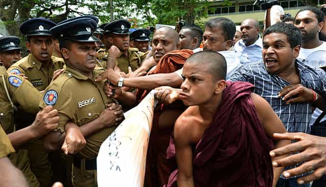 A group of [Power of Ravana] Buddhist monks push through police barricades to march during a demonstration outside the UN office in Colombo on August 26, 2013, denouncing human rights chief Navi Pillay on the first full day of her visit to Sri Lanka. The UN's top rights official began her visit to Sri Lanka on August 25, by brushing aside criticism that she overstepped her brief and vowing to raise human rights concerns with Colombo. (Photo by Ishara S. Kodikara/AFP Photo)