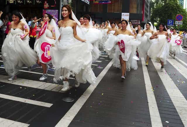 Women in wedding gowns participate in a brides' race organized by a shopping mall to celebrate the upcoming Qixi Festival in Guangzhou, China, on August 12, 2013. The Qixi Festival, also known as the Double Seven Festival, which falls on the seventh day of the seventh month in the Chinese lunar calendar, is the Chinese version of Valentine's Day. The festival falls on August 13 this year. (Photo by Reuters)