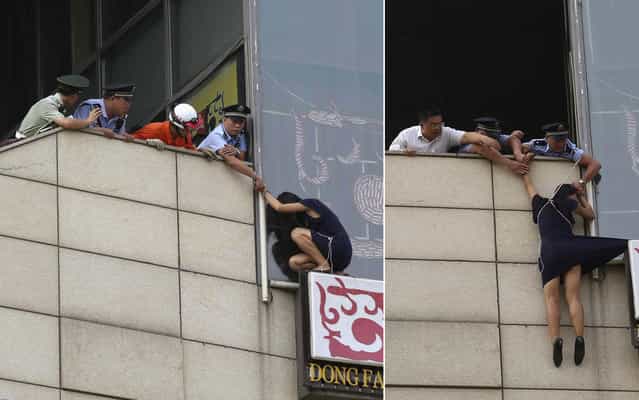 A police officer saves the life of a suicidal woman by handcuffing himself to her and throwing away the key. The desperate woman had climbed to the top of a bill board on a concrete wall in Beijing, China, on August 14, 2013. But her plight quickly attracted the attention of bystanders and police arrived to try and talk her down. When one of the officers was talking to her, he decided the only way to make sure she did not jump was by handcuffing himself to the woman. As the woman hung from the ledge the officer put the metal cuff across his wrist and the connected it to the woman. And in a determined bid to make sure she realised he was serious about saving her, he then threw the key over the ledge so they could not be separated. Police then used a length of rope to pull the woman back onto the building as she dangled above a sheer drop to the concrete pavement held by just her wrist. (Photo by Reuters/China Daily)