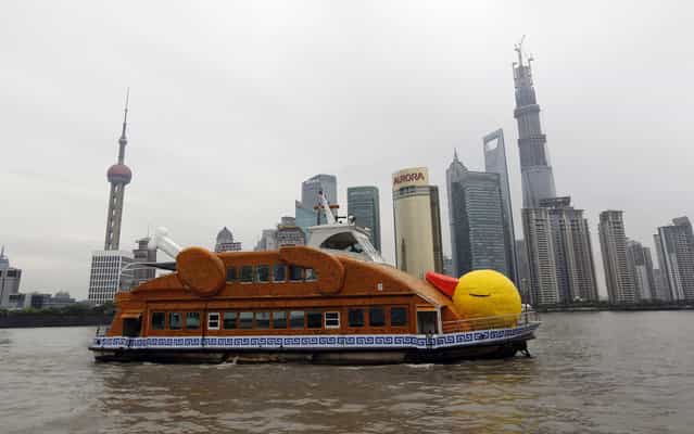 A ferry in the shape of a duck is seen on the Huangpu River in front of the Pudong Financial area in Shanghai, August 26, 2013. The ferry was designed and remade by several Chinese artists, who claimed they were paying tribute to Dutch conceptual artist Florentijn Hofman's creation [Rubber Duck]. The ferry will be on exhibition for a month as part of the Bund Art Project of 2013, local media reported. (Photo by Aly Song/Reuters)