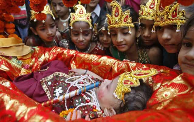 Schoolgirls dressed as Radha, the consort of Hindu Lord Krishna, look at a child dressed as Krishna during the celebrations to mark Janmashtami festival in Ahmedabad, India, on August 27, 2013. The festival, which marks the birth anniversary of Lord Krishna, will be celebrated across India. (Photo by Amit Dave/Reuters)