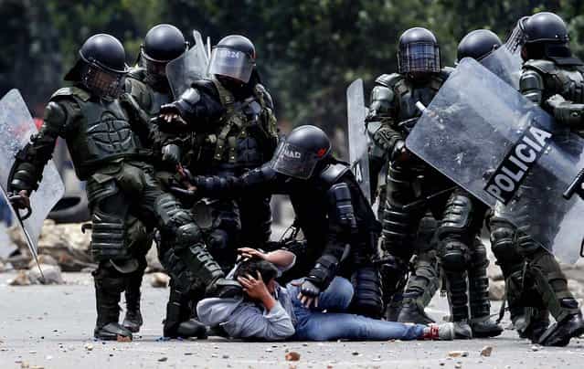A police officer kicks a protester as another, tries to protect him before his arrest during protests in Ubate, north of Bogota, Colombia, on August 26, 2013. Hundreds of protesters clashed with police in support of farmers who have being blockading Colombian highways for a week for an assortment of demands that include reduced gasoline prices, increased subsidies and the cancellation of free trade agreements. (Photo by Fernando Vergara/Associated Press)