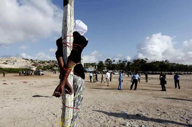 Adan Sheikh Abdi Sheikh, sentenced to death for the murder of journalist Hassan Yusuf Absuge, stands tied to a pole before he is executed by shooting at close range at Iskola Bulisiya Square in Mogadishu, on August 17, 2013. (Photo by Feisal Omar/Reuters)