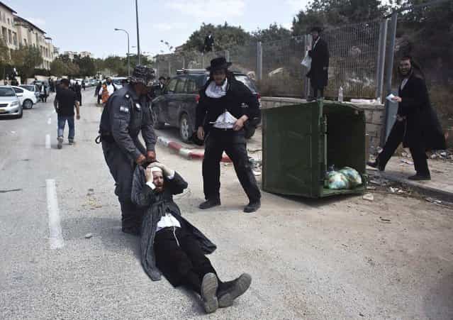 An Israeli policeman drags an ultra-Orthodox man during clashes in the town of Beit Shemesh, near Jerusalem August 12, 2013. An Israeli police spokesperson said some 21 ultra-Orthodox protesters were detained on Monday in the town during clashes with police after a group of them broke into a construction site to prevent work from taking place at the site they believe contains ancient graves. (Photo by Nir Elias/Reuters)