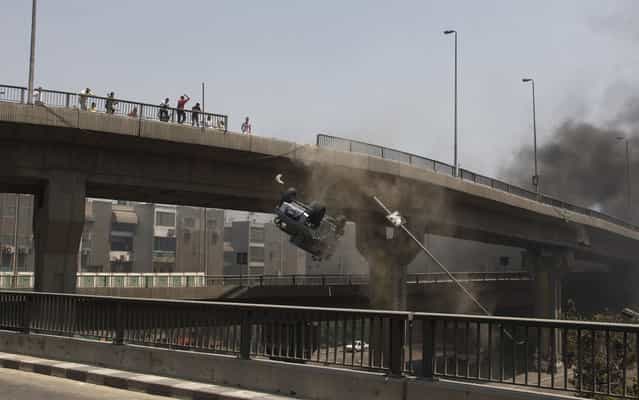 A police vehicle is pushed off of the Sixth of October Bridge in Cairo on August 14, 2013. (Photo by Sabry Khaled/AP Photo/El Shorouk Newspaper)