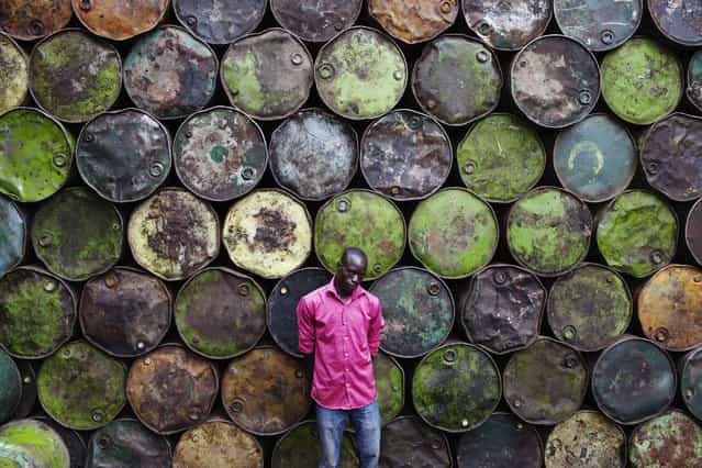 Steel barrel vendor Lassiney Diarra poses for a picture in front of barrels in Bamako August 13, 2013. (Photo by Joe Penney/Reuters)