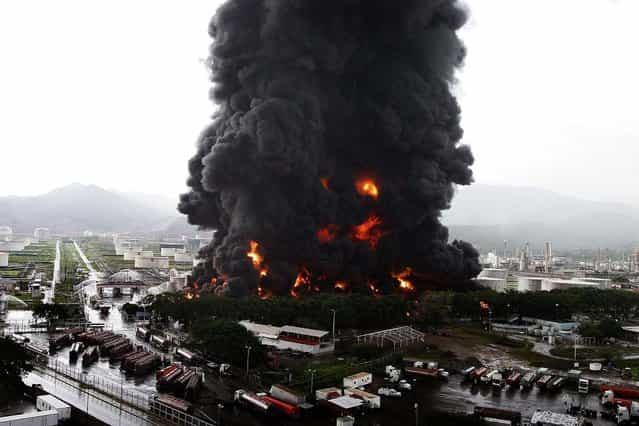 Firefighters try to extinguish a fire at an oil refinery in Puerto La Cruz, Venezuela, on August 11, 2013. Lightning set fire to a storage tank at the refinery, and residents were moved out of the immediate area. (Photo by Reuters)