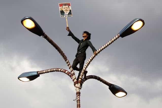 A supporter of deposed Egyptian President Mohamed Mursi climbs up a lamp post during a march in Sanaa, Egypt, on August 16, 2013. (Photo by Mohamed al-Sayaghi/Reuters)