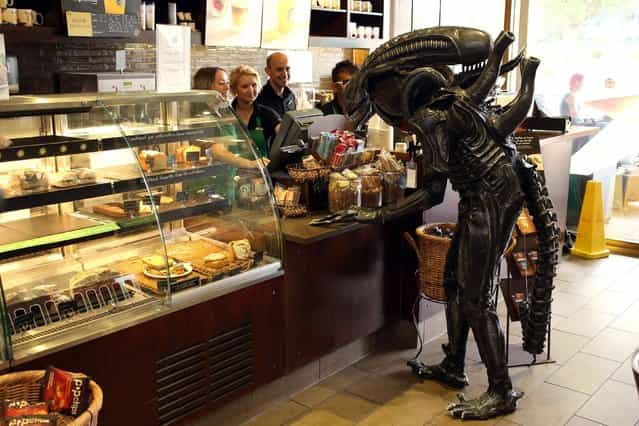 A Si-Fi enthusiast dressed as the alien from the iconic science fiction film Alien poping into a Starbucks as he attends the Nine Worlds Geekfest at the Radisson Hotel near Heathrow, on August 11, 2013. It is a weekend-long, multi-genre, residential event for sci-fi convention fans. (Photo by Steve Parsons/PA Wire)