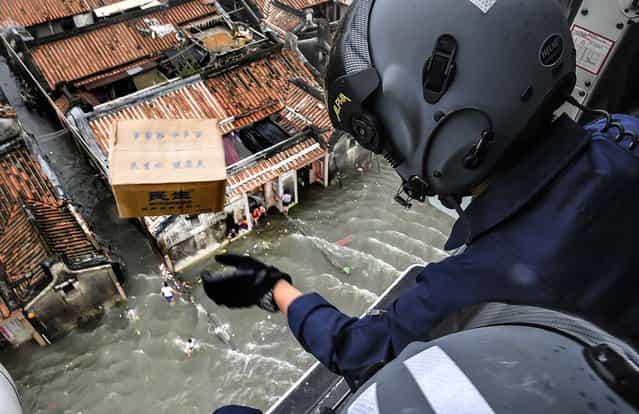 A rescue worker throws a box containing water out of a helicopter above a flooded area in Shantou, Guangdong province, China, on August 21, 2013. Flooding triggered by rainstorms have ravaged the city for the last few days, affecting 772,000 people across 11 townships, according to local media. (Photo by China Daily)