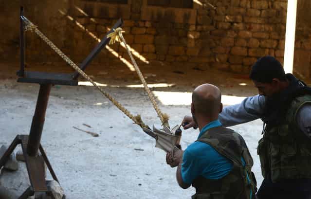 Syrian rebels prepare to launch a bomb using a homemade slingshot in the northern city of Aleppo, on October 16, 2012. Lightly-armed Syrian rebels who face the warplanes, artillery and tanks of loyalists have turned to making their own weapons, even rigging a video game controller to fire mortar rounds. (Photo by Tauseef Mustafa/AFP Photo)