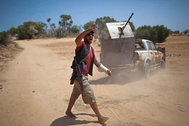 A rebel fighter in front of an armored technical gives orders to comrades at the front line between the rebels and pro-Qaddafi forces, 25 km west of Misurata, on May 26, 2013. (Photo by Rodrigo Abd/AP Photo)