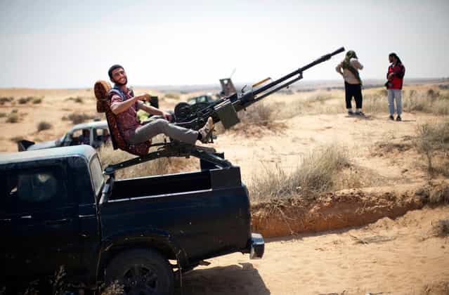 A rebel fighter rests on a weapon mounted on the back of a pickup truck on the front line between them and Muammar el-Qaddafi forces, 30 km south of Misurata, on May 27, 2013. (Photo by Rodrigo Abd/AP Photo)