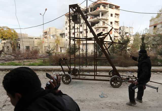 A [Free Syrian Army] fighter uses a catapult to fire a homemade grenade at Syrian Army soldiers during a fight in the Arabeen neighborhood of Damascus, on January 24, 2013. (Photo by Goran Tomasevic/Reuters)