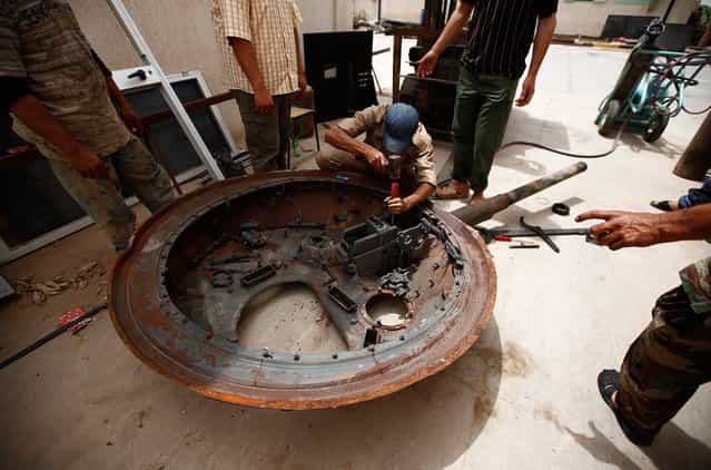 A Libyan man tries to remove a cannon from a part of a tank, belonging to forces loyal to Libyan leader Muammar el-Qaddafi, with plans to reuse it, in the western Libyan city of Misurata, on June 7, 2013. (Photo by Zohra Bensemra/Reuters)