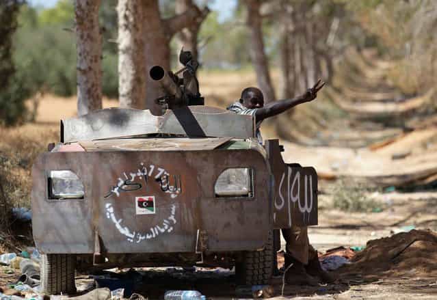A Libyan rebel fighter, in a vehicle rigged with armor plating, flashes a victory sign at a territory taken from forces loyal to Muammar el-Qaddafi, after rebels pushed several kilometers in the direction of Zliten, west of the rebel-held port city of Misurata, on June 13, 2013. (Photo by Zohra Bensemra/Reuters)