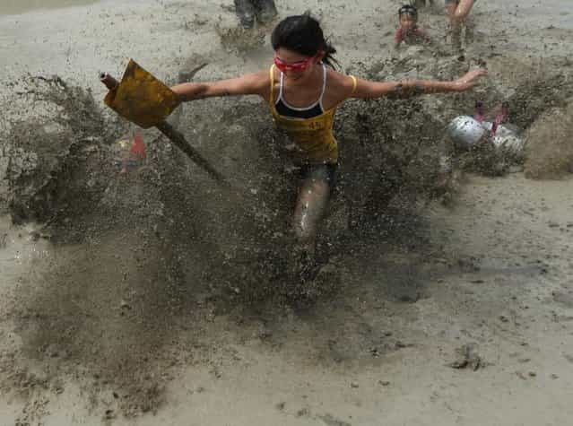 Japanese festival-goer runs to catch a flag during the village mud festival at Yumesaki on August 18, 2013 in Himeji, Japan. The festival has been held annually to encourage youths of the village to participate in the community. (Photo by Buddhika Weerasinghe/Getty Images)