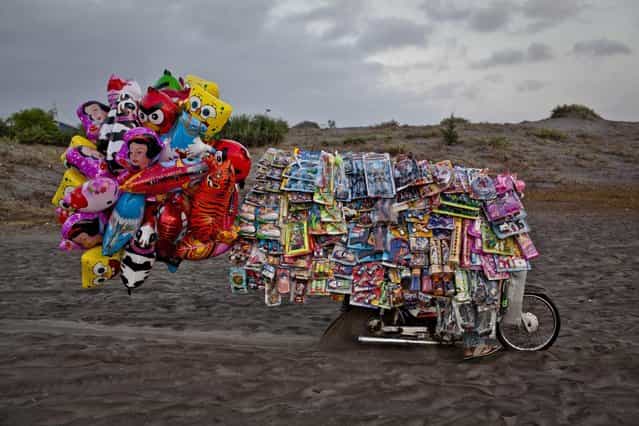 A toy seller rides on [sea of sands] as Indonesian muslims people perform Eid Al-Fitr prayer at Parangkusumo beach on August 8, 2013 in Yogyakarta, Indonesia. Eid Al-Fitr, marks the end of Ramadan, the Islamic month of fasting and begins after the sighting of a new crescent moon. (Photo by Ulet Ifansasti/Getty Images)