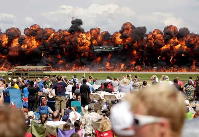 A World War II American plane flies in front of a wall of fire as it takes part in a re-enactment of the attack on Pearl Harbor during an afternoon air show at the EAA AirVenture at Wittman Regional Airport in Oshkosh, Wisconsin August 3, 2013. (Photo by Darren Hauck/Reuters)