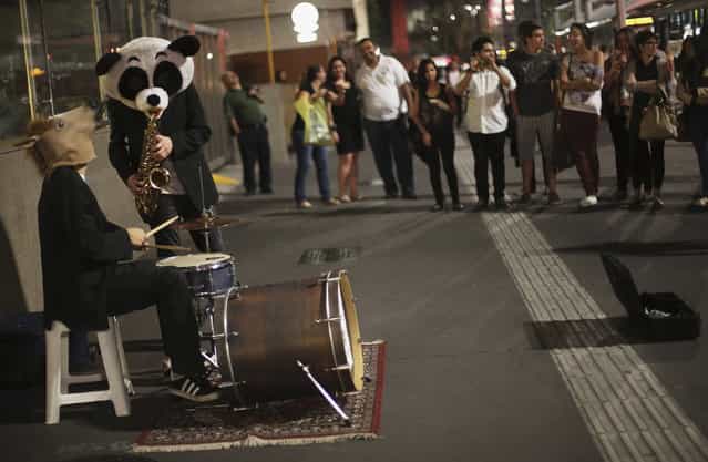 Street musicians, with a horse and panda masks, play the saxophone and drums as they perform in the financial center in Sao Paulo's Avenida Paulista August 9, 2013. (Photo by Nacho Doce/Reuters)