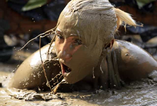 A competitor crawls through mud water during a Fighters' Run competition in Zanka, 150 km (93 miles) west of Budapest, August 10, 2013. (Photo by Laszlo Balogh/Reuters)
