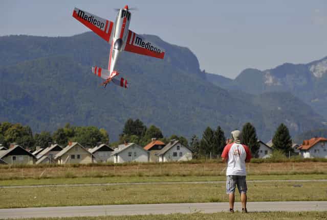 A man flies his model plane during an airshow for radio-controlled airplanes at Lesce airport, August 15, 2013. (Photo by Srdjan Zivulovic/Reuters)